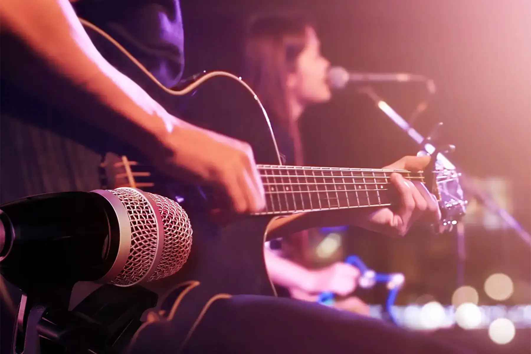 Close up of accoustic guitar being played on stage during a live concert performance in the showroom.