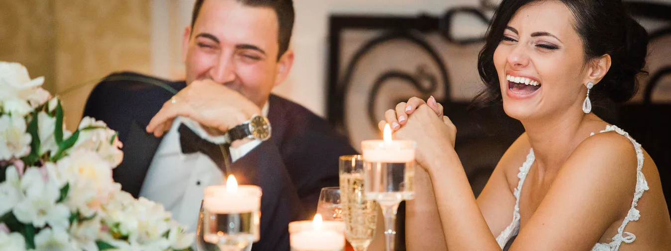 bride and groom smiling and laughing at their table with candles